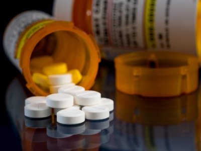 a close up of a tipped over orange container with white pills spilling onto a black surface